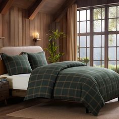 a bed in a bedroom next to a window with wood paneling and wooden walls