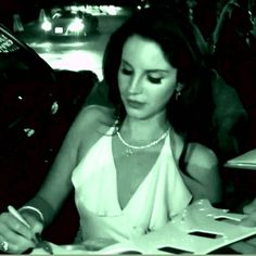 a woman sitting at a table writing on a piece of paper