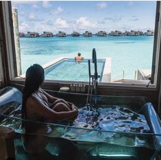 a woman is sitting in the jacuzzi looking out at the water and people swimming