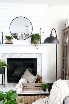 a living room with a white fireplace and lots of greenery