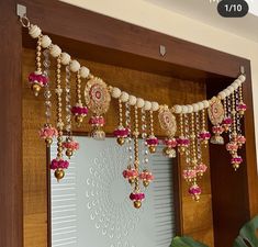 a wooden door decorated with pink and gold jewelry hanging from it's side, next to a potted plant