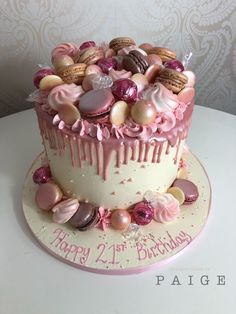 a birthday cake decorated with pink icing and lots of macaroons