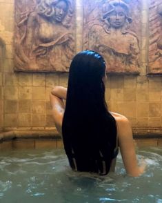 a woman is sitting in the water with her back turned