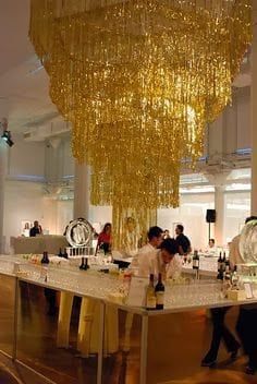 a chandelier hanging from the ceiling in a room with people standing around it