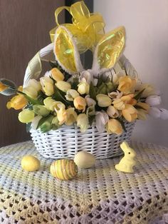 a basket filled with yellow and white tulips on top of a crocheted table