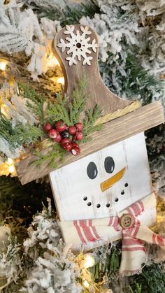 a wooden snowman ornament hanging from a christmas tree