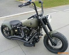 a green motorcycle parked on the street next to a sidewalk with grass in the background