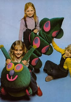 three children sitting on the ground with stuffed animals in front of them and one child holding an animal