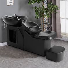 a black chair sitting next to a sink in a room with a potted plant