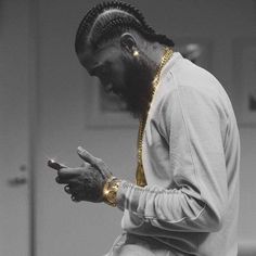 a man sitting on top of a couch using a cell phone while wearing a gold necklace