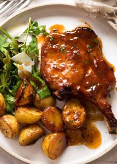 a white plate topped with meat and potatoes covered in gravy next to a salad