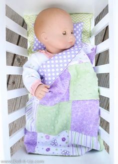 a baby doll laying in a crib with a blanket on it's back