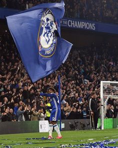 a man holding a blue flag on top of a soccer field