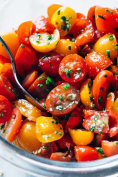 a glass bowl filled with tomatoes and herbs