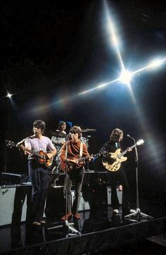 the beatles performing on stage with their guitars