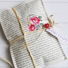 an open book with flowers on it and a tag attached to the pages that have been folded