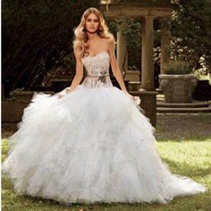 a woman in a white wedding dress standing on the grass with her hands behind her back