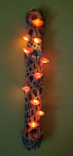 there are many lit candles in the shape of a pillar on the wall with holes