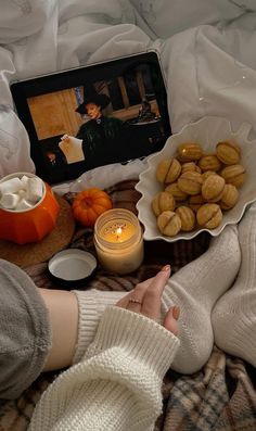 a person sitting on a bed with food and candles in front of them next to a photo