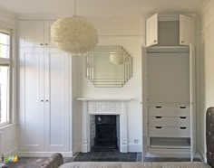 a bedroom with white furniture and a fireplace