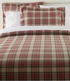 a bed with plaid sheets and pillows on it