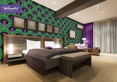 a large bed sitting in the middle of a bedroom next to a purple and green wall