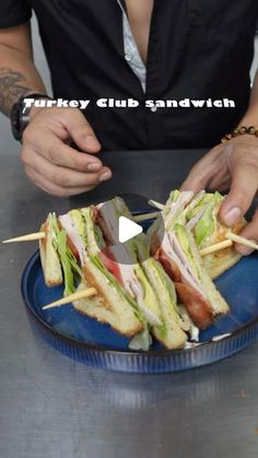 a man is cutting into sandwiches with toothpicks on a blue plate that reads turkey club sandwich