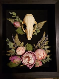 an animal skull and flowers in a black frame