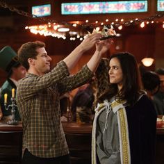 a man and woman standing next to each other in front of a bar with lights