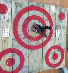 scissors are stuck in the center of a wooden target board with red and white circles on it