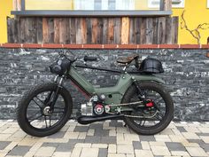 a green motorcycle parked in front of a brick wall with a helmet on it's seat