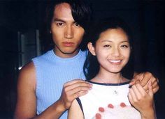 a man standing next to a woman in a blue tank top and smiling at the camera