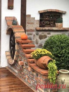 a brick wall with pots and pumpkins on the ledge next to an old wheel