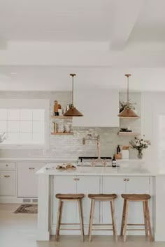 a kitchen with two stools and an island in the middle of it, surrounded by white cabinets