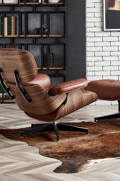 an eames chair and ottoman in front of a brick wall with bookshelves