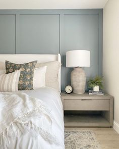 a white bed sitting next to a night stand with two lamps on each side of it