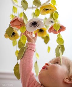 a baby is playing with some flowers on the phone screen and text reads felt flower mobile free printable