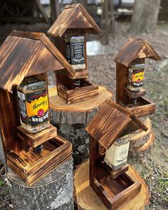 three bird houses made out of wood with honey jars in them sitting on top of tree stumps