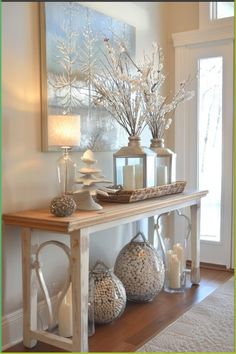 a wooden table topped with vases filled with flowers next to a painting on the wall