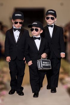 three little boys dressed in black suits and hats, one holding a bag while the other is wearing sunglasses