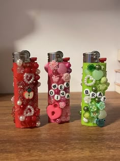 three different colored lighters sitting on top of a wooden table next to each other