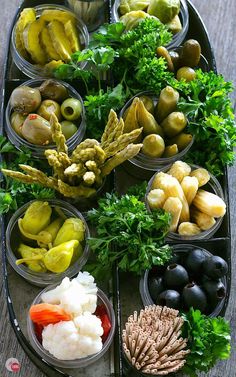 an assortment of different types of food in plastic containers on a tray with pine cones