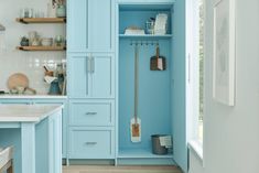 a kitchen with blue cupboards and white counter tops, wooden floors and open shelving