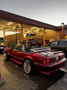 a red sports car parked in front of a gas station with other cars behind it