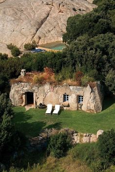 an aerial view of a stone house in the mountains with grass and trees around it