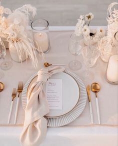 the table is set with white and gold place settings