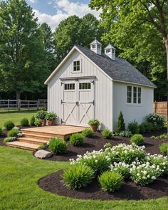 a small white shed sitting in the middle of a lush green field