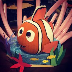 an inflatable clown fish sitting on top of a table next to pink sticks