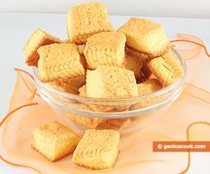 a glass bowl filled with short crackers sitting on top of a white tablecloth