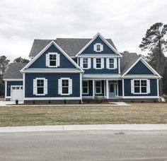 a large blue house with white trim on the front and side windows is shown in this image